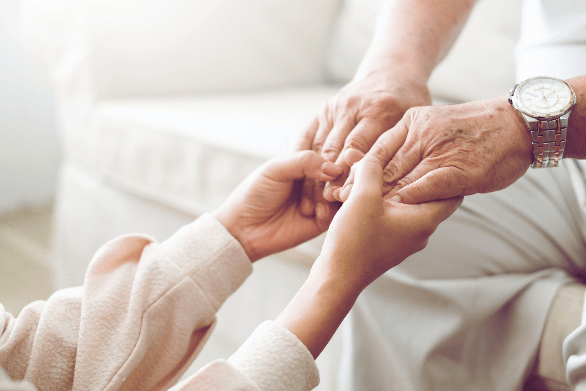 Senior sharing wisdom to younger person while holding both hands