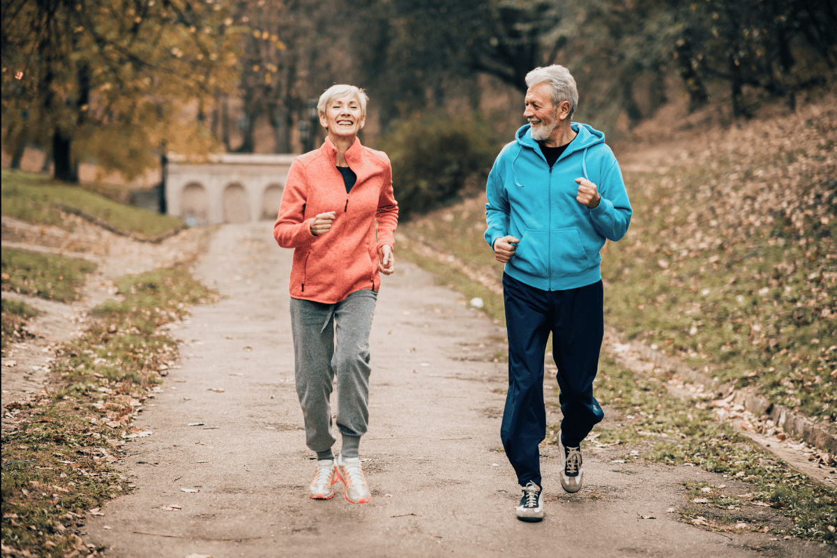 Elderly woman and man jogging on a sidewalk