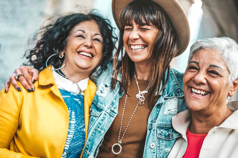 Three senior women having fun laughing out loud outside - Happy female friends talking together walking on city street - Life style concept with mature females hanging outdoors on summer holiday