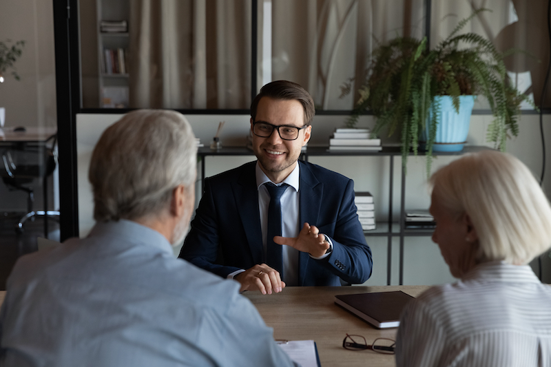 Happy confident lawyer, realtor, notary, financial advisor giving consultation, legal advice to senior couple of clients about medical insurance, wills, house buying or selling, savings, investment