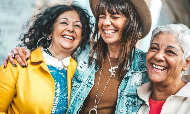 Three senior women having fun laughing out loud outside - Happy female friends talking together walking on city street - Life style concept with mature females hanging outdoors on summer holiday